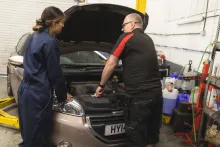 A young and old mechanic working on a Peugeot 208